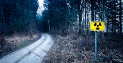 森林小路旁，阴沉环境中的辐射警告标志