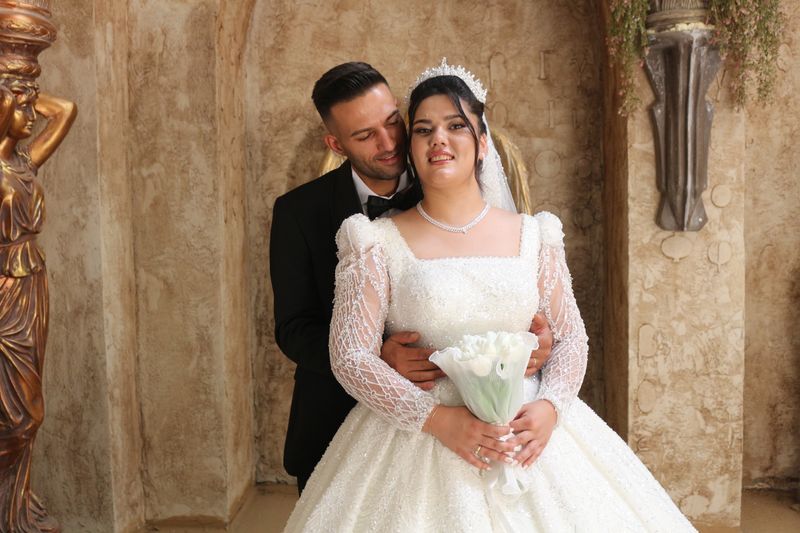Pasangan pengantin elegan berpose di dalam ruangan klasik