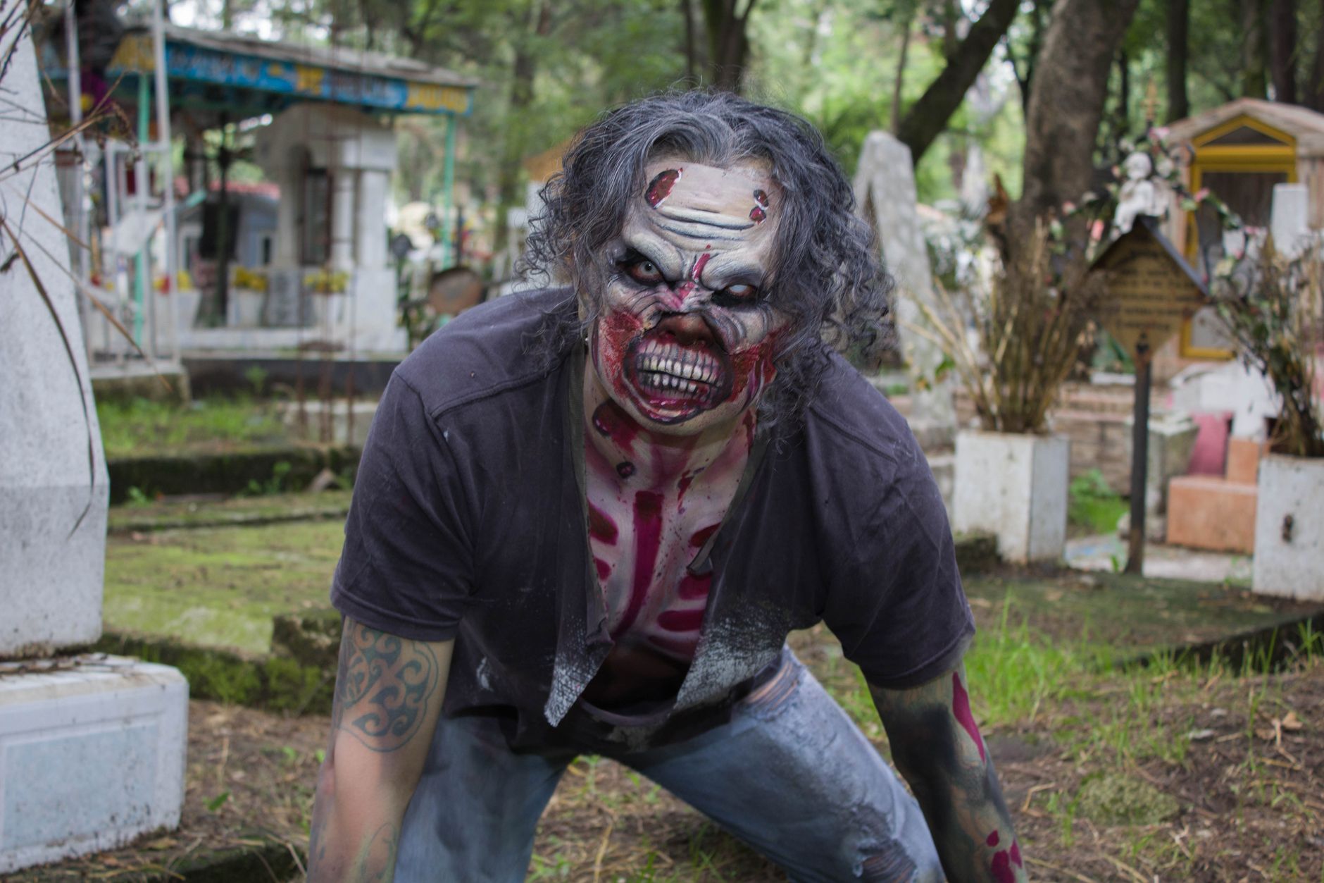 A terrifying zombie character in a cemetery, captured during daylight in Mexico City.
