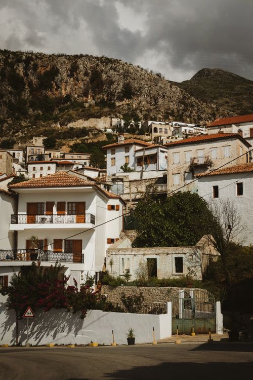 Free Traditional whitewashed buildings in Dhërmi, Vlorë County, Albania under a cloudy sky. Stock Photo