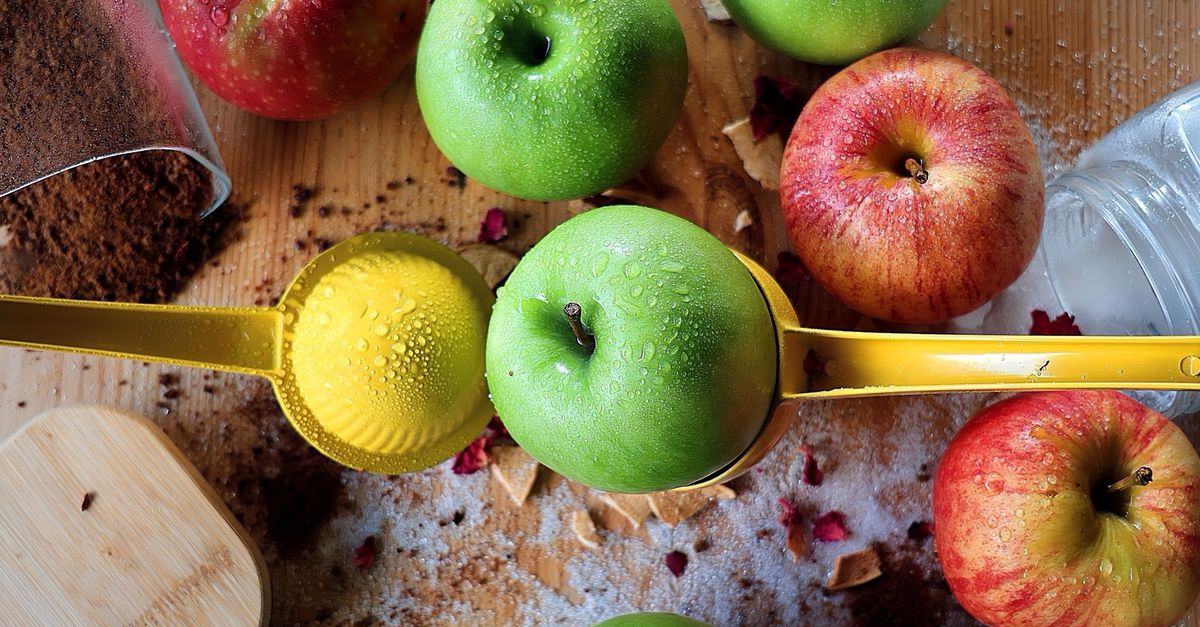 Top view of dewy green and red apples with a yellow juicer on a wooden surface. - Evidence evidence guide for apple cider vinegar exercise performance randomized trial