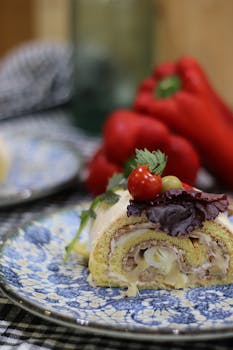 Close-up of a savory roll with toppings on a blue floral plate, with peppers in the background.