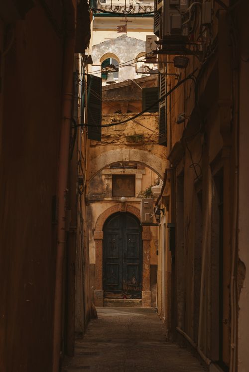Free Discover the quaint charm of Corfu's old town with a rustic door along a narrow street. Stock Photo
