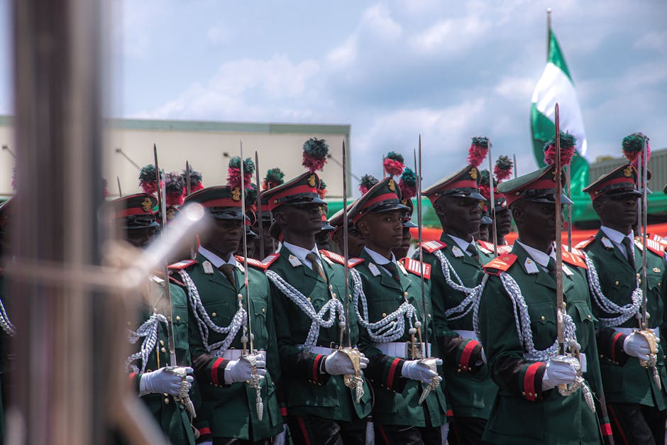 Nigerian soldiers in ceremonial uniform participate in a formal parade outdoors.