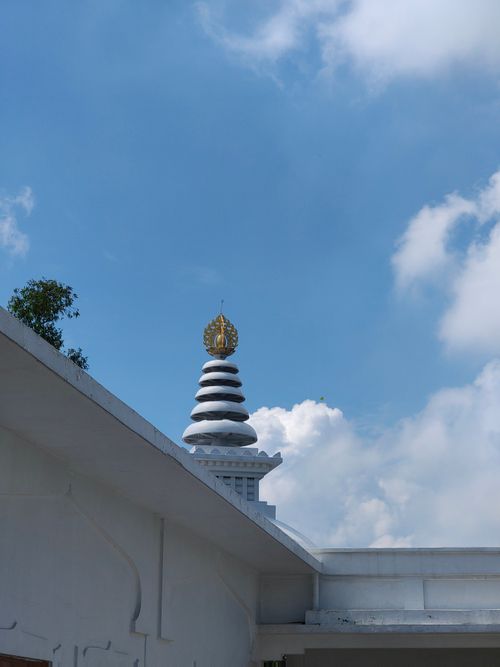 Free A traditional Thai temple spire reaching into a bright blue sky with scattered clouds. Stock Photo