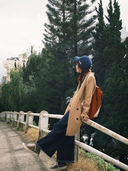 Woman in casual attire enjoys a peaceful moment by a green tree-lined path.