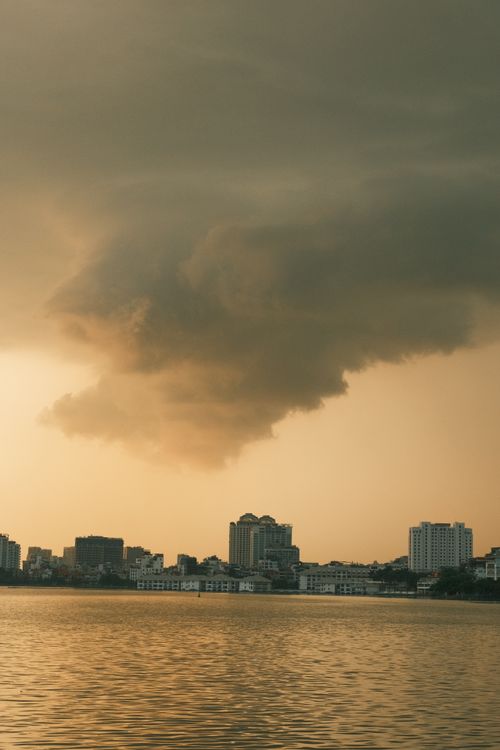Free Moody sky and urban skyline over water in Jakarta, Indonesia at sunset. Stock Photo