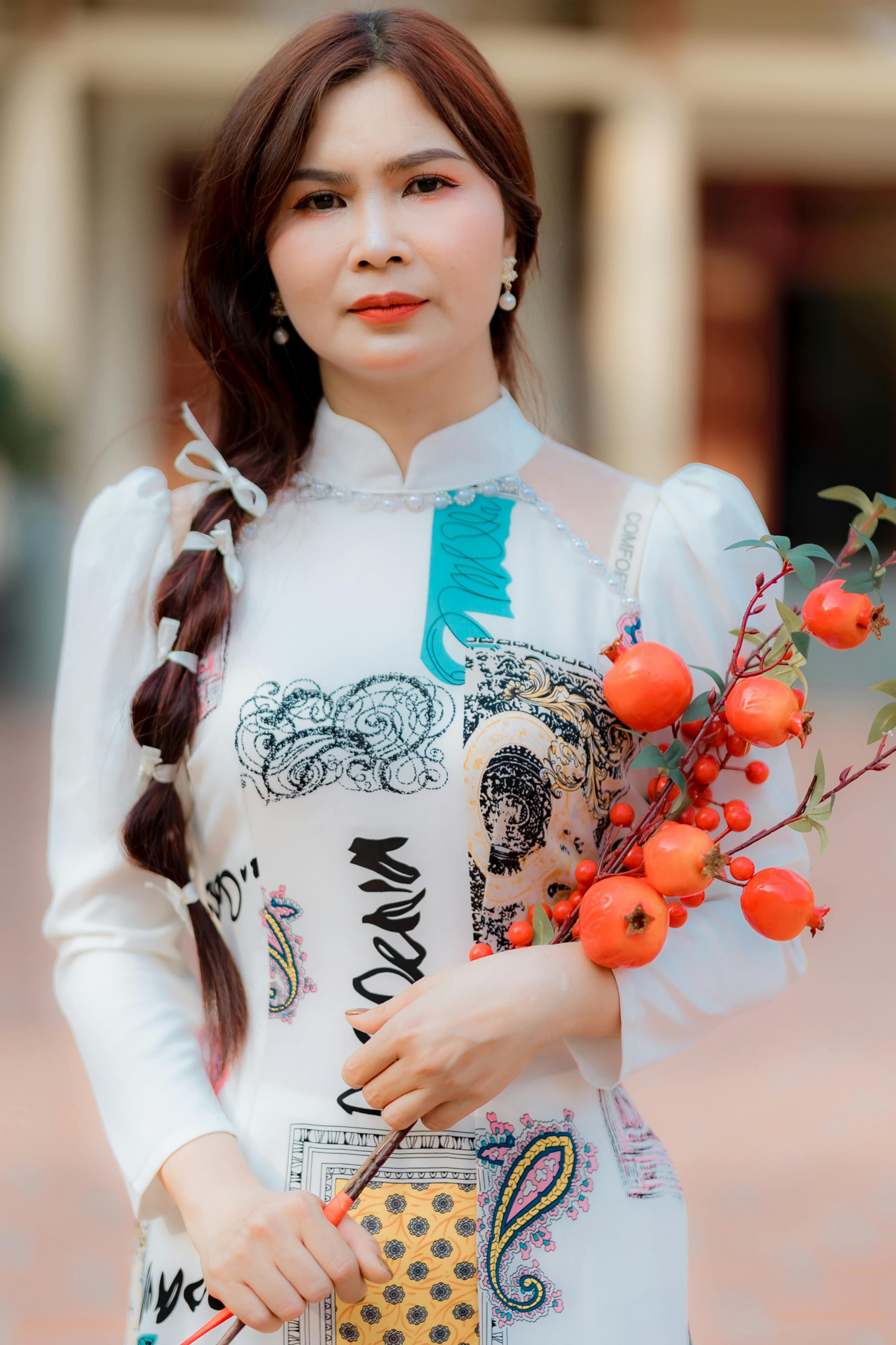 Portrait of a woman in traditional attire holding red berries, showcasing elegance and style.