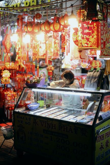 Colorful night scene of a Chinese market stall with bright decorations and lanterns.