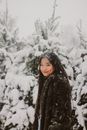 白雪皑皑的树林中，一个女人微笑着，营造出宁静的冬季景观