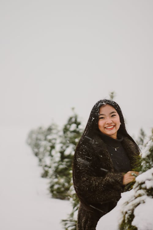 Woman in Black Scarf and Black Coat Standing on Snow Covered Ground