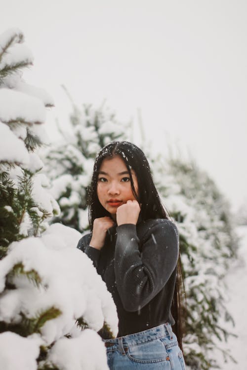 Selective Focus Photography of Woman Standing Beside Snow-covered Trees