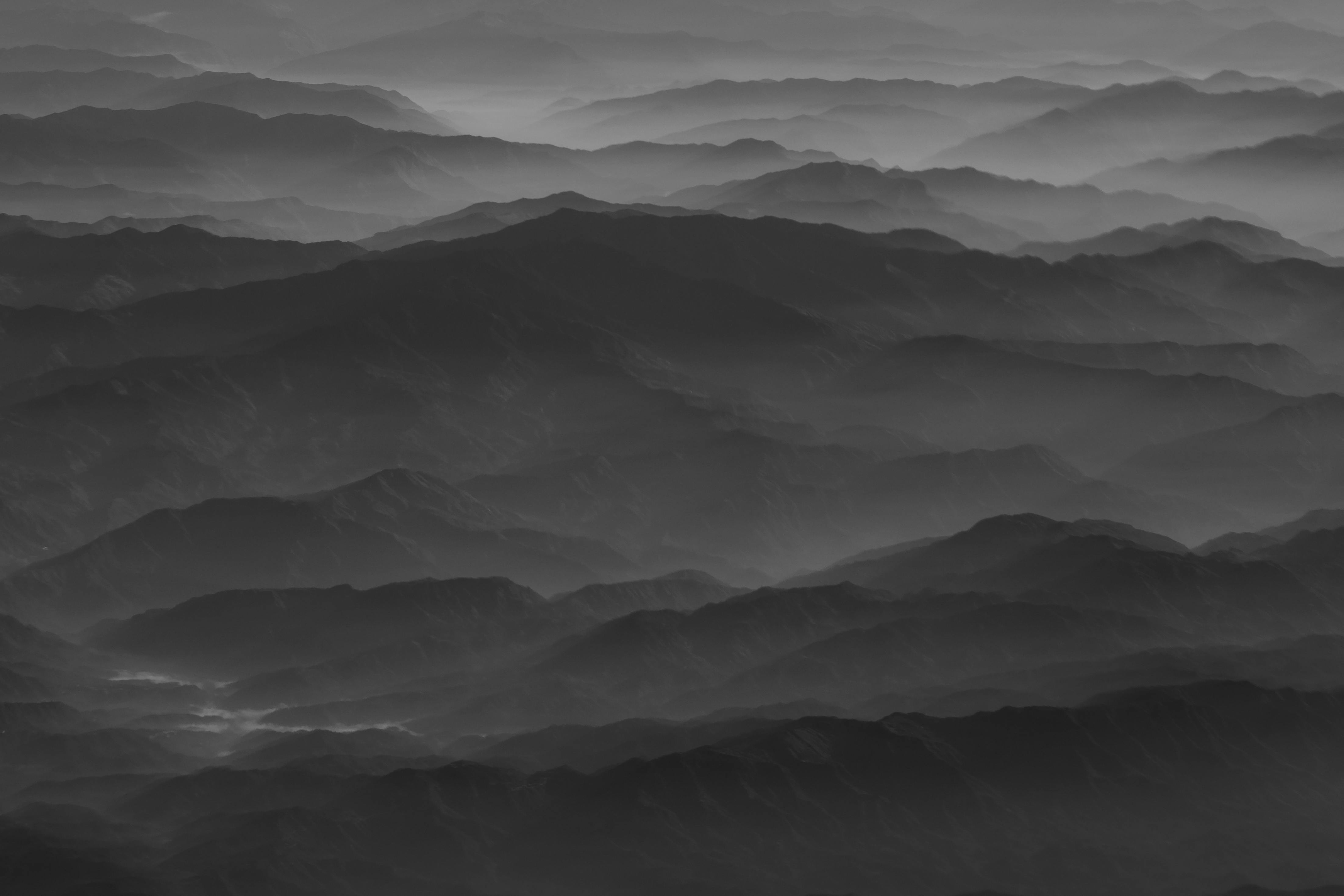 黑白照片中，雾气缭绕的山脉营造出宁静的风景