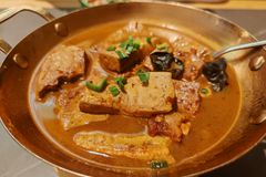 Close-up of braised tofu in a rich brown sauce with scallions and black mushrooms.