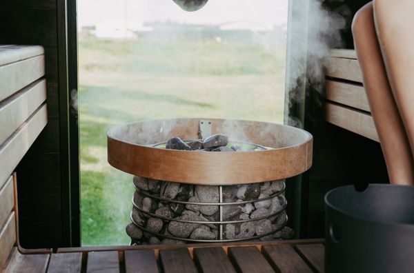 Steam rising from hot sauna stones on cedar bench — the authentic sauna experience inside every Cedar & Steam build