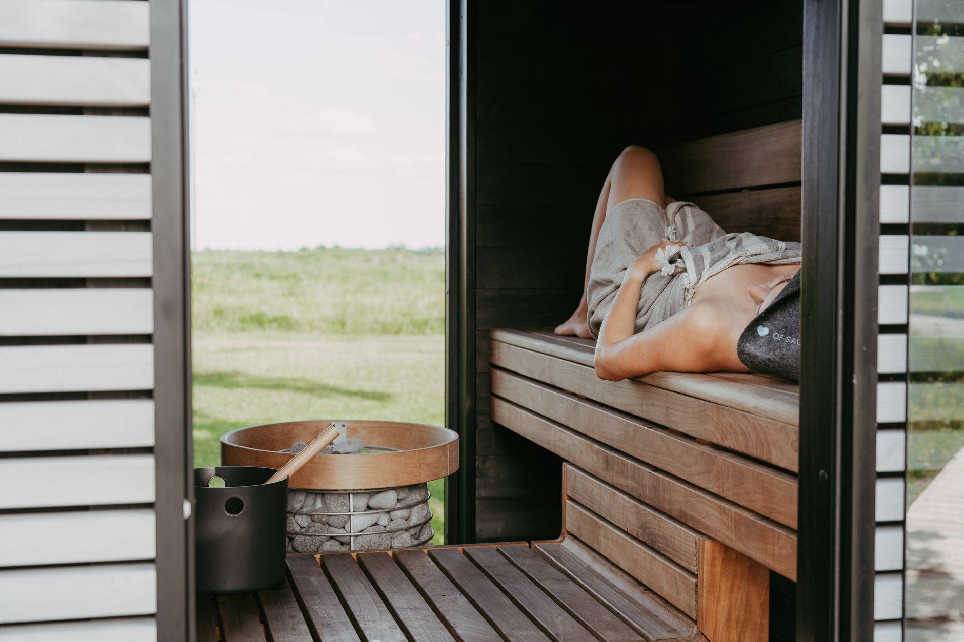 Person meditating in a sauna, combining heat therapy and mindfulness.