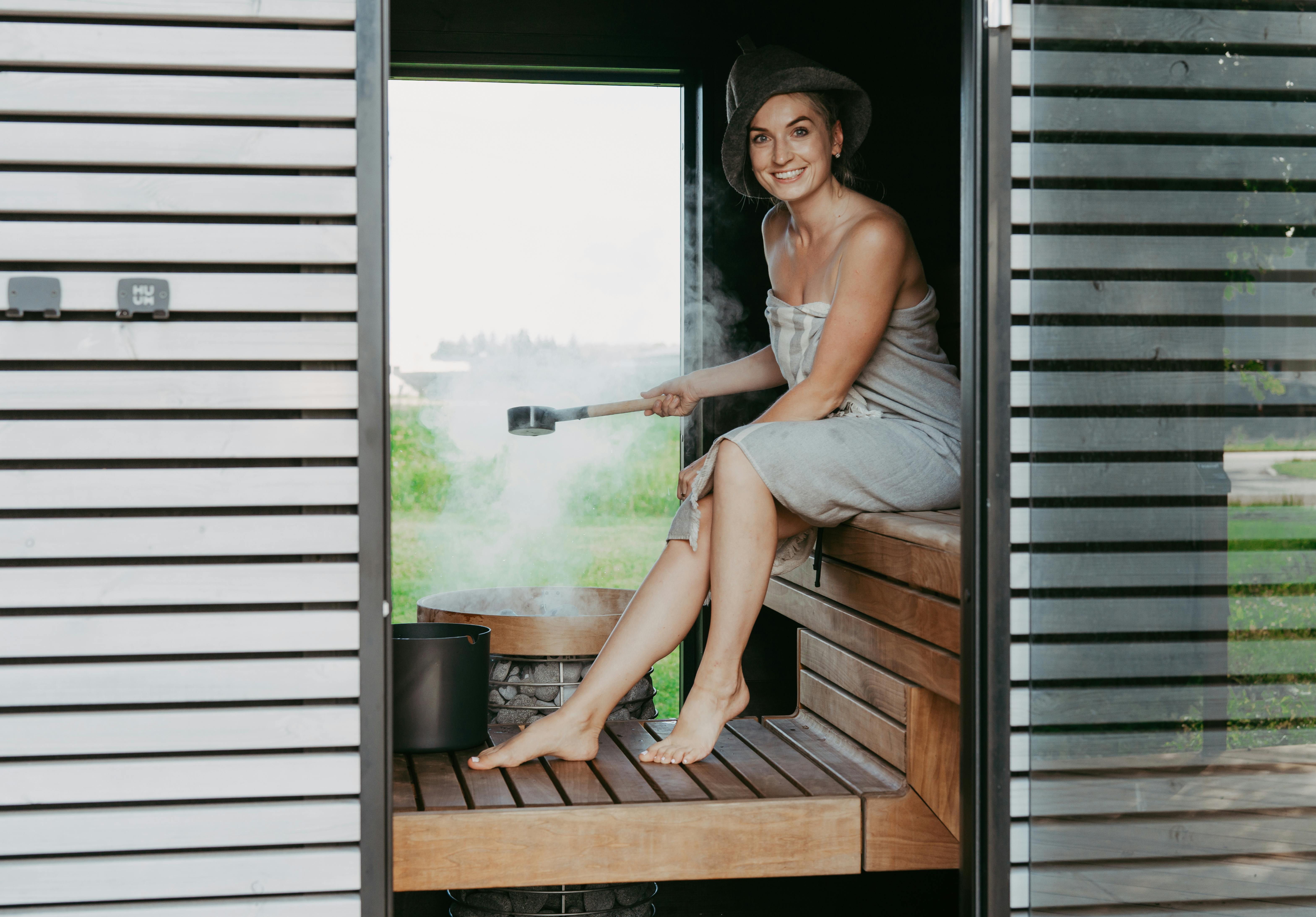 A woman happily relaxes in a stylish sauna, emphasizing comfort and modern design.