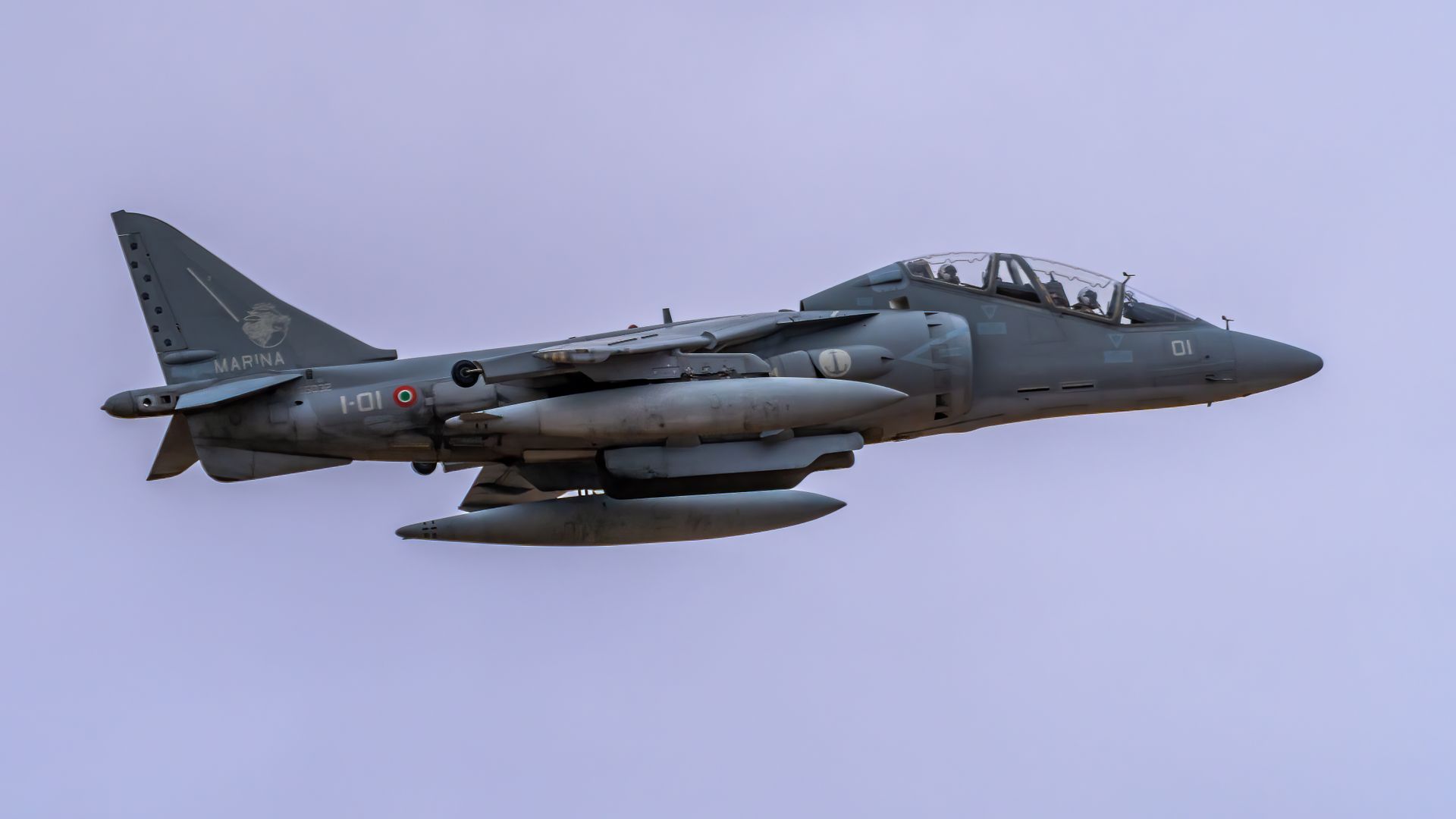 A military jet aircraft flying through a clear blue sky during daytime.