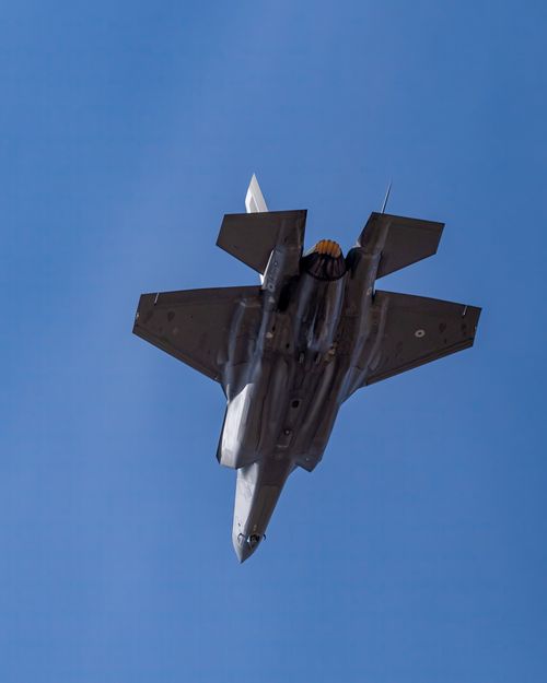 Free Majestic F-35 fighter jet flying high against a clear blue sky in Los Llanos, Spain. Stock Photo