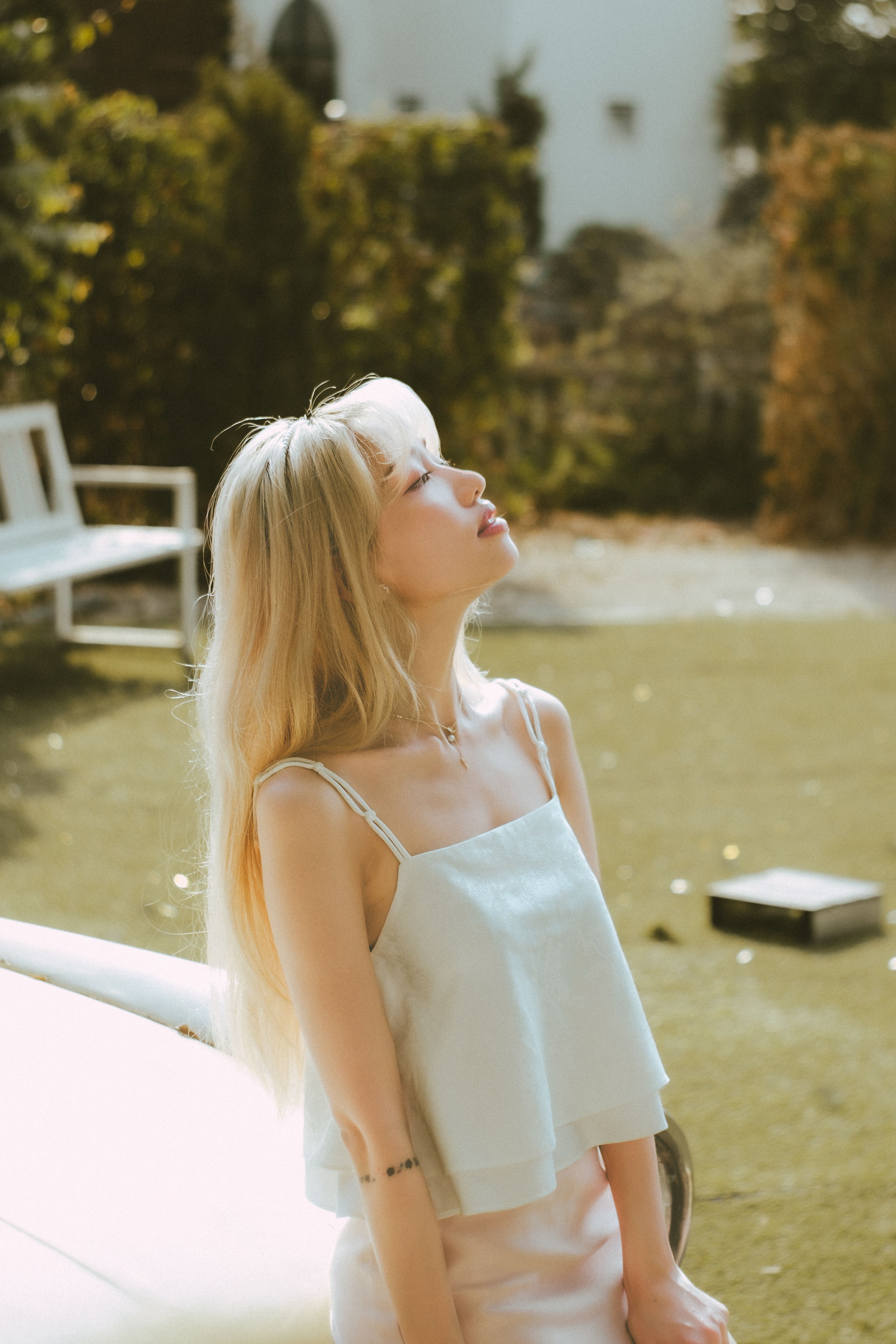 A young woman enjoys sunlight in a garden, creating a serene and warm atmosphere.