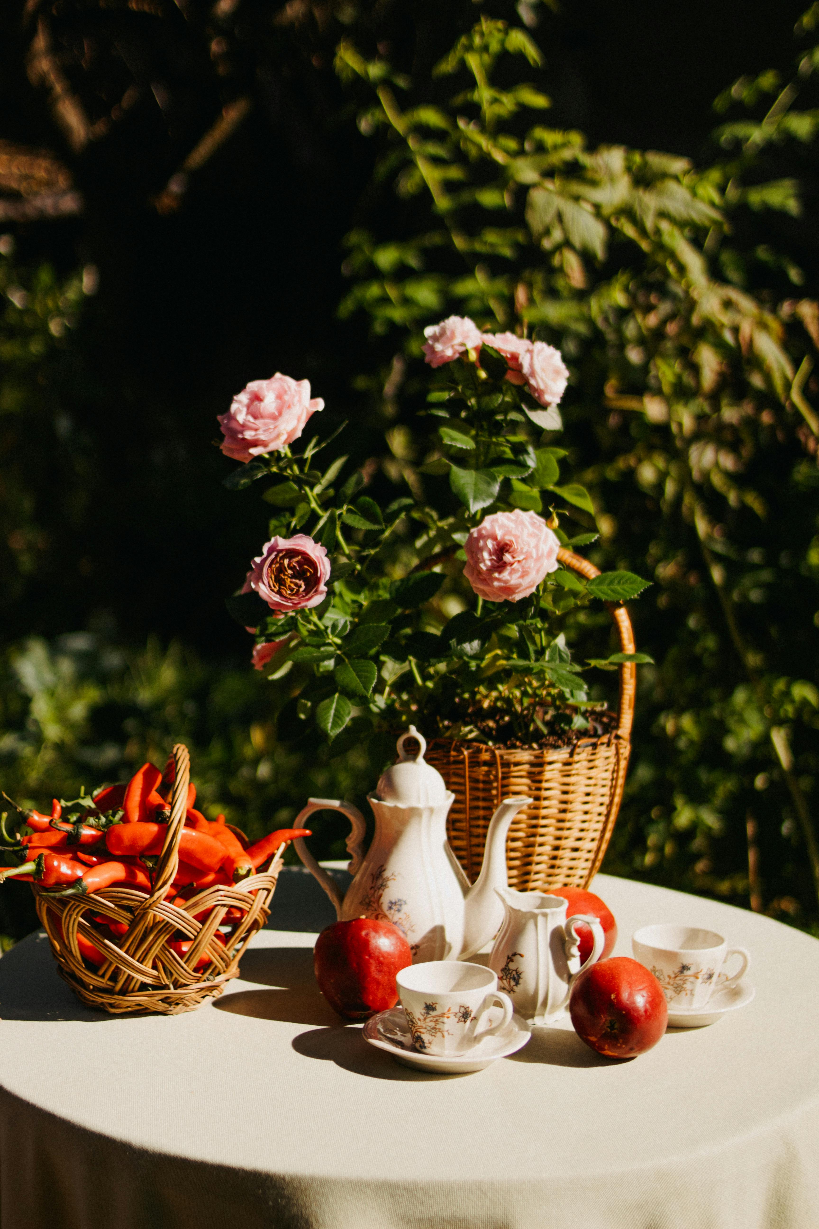 A charming outdoor tea setup with roses, fruit, and china, perfect for spring serenity.