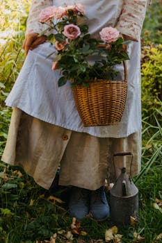A woman in a vintage dress holds a basket of pink roses in a lush garden setting.