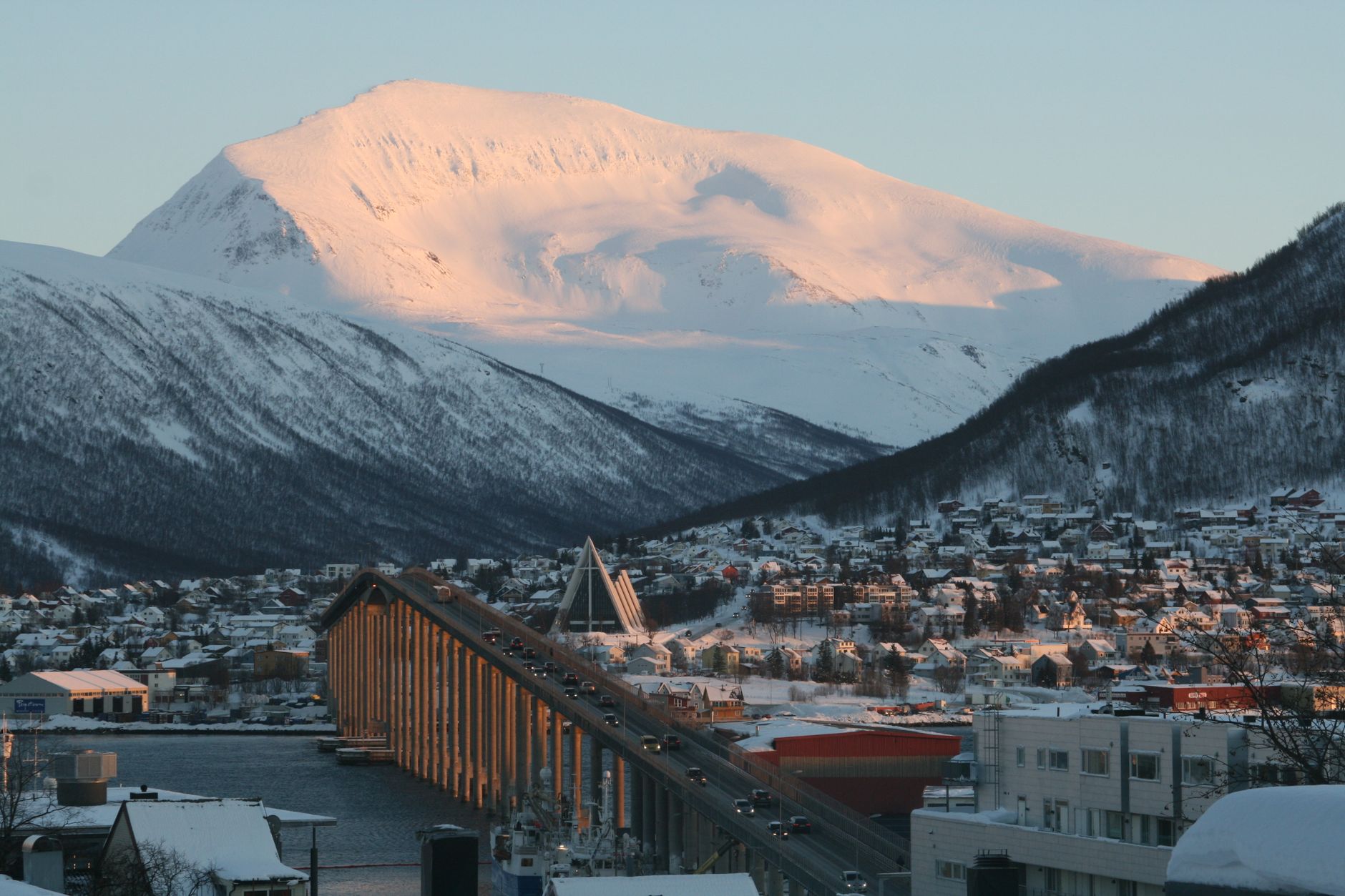 Tromsø under snow-covered mountains at winter sunset, Norway