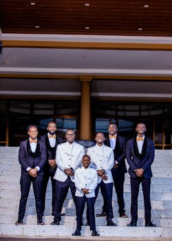 A group of men in formal attire posing confidently on steps, showcasing style and elegance.