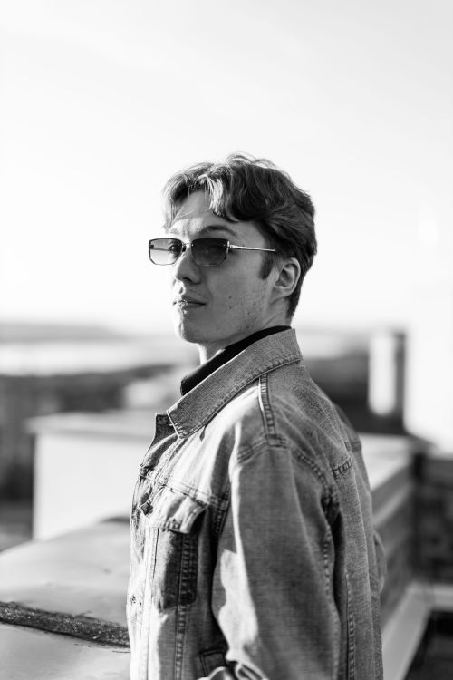 Free Stylish young man in sunglasses and denim jacket, creating a classic black and white portrait. Stock Photo