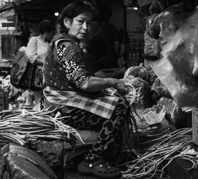 An intimate black and white portrayal of a local vendor in a bustling market in Baguio, Philippines.