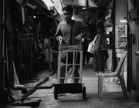 A dramatic black and white photograph of a market scene with a man using a cart, revealing daily life in Baguio, Philippines.