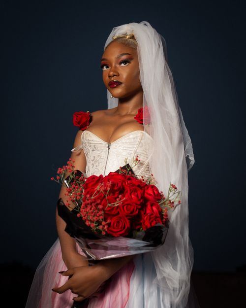 Free Beautiful African bride holding a bouquet of red roses, wearing a veil and white dress. Stock Photo