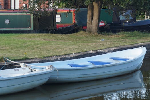 A serene view of boats docked along the canal in Eccles, England, surrounded by nature.