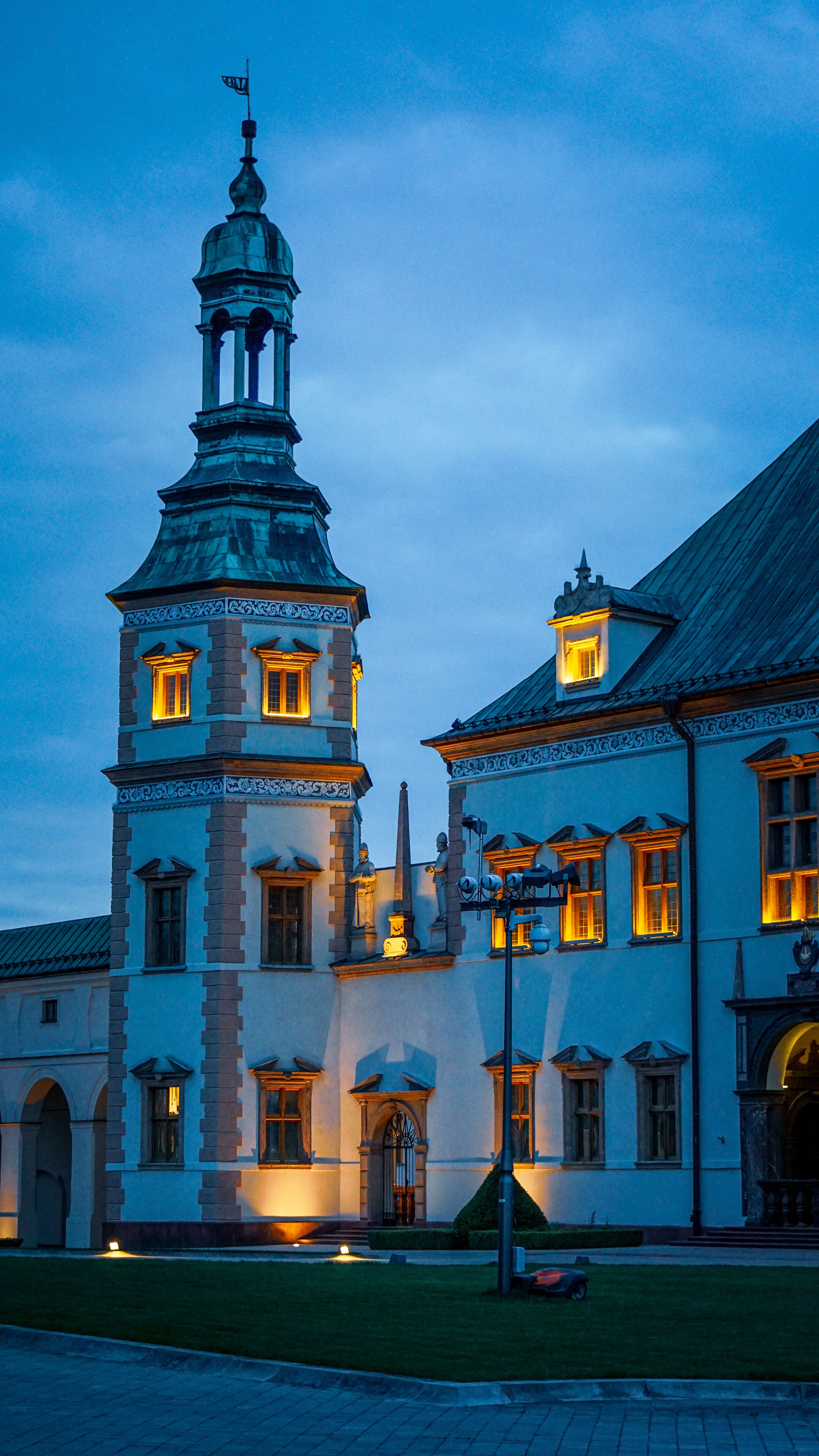 Illuminated Baroque palace in Kielce, Poland, captured at twilight showcasing stunning architecture.