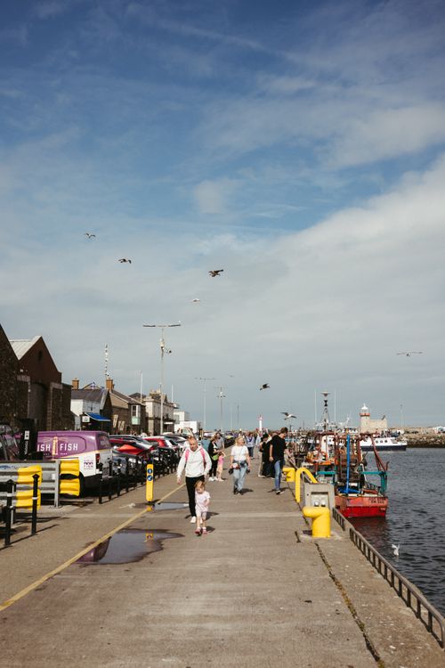 Free A sunny day at Howth Harbour Pier in Dublin, Ireland, with people enjoying the scenic walk. Stock Photo