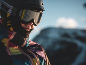 雪地里，一位穿着彩色服装、戴着滑雪镜的冬季冒险家的特写镜头