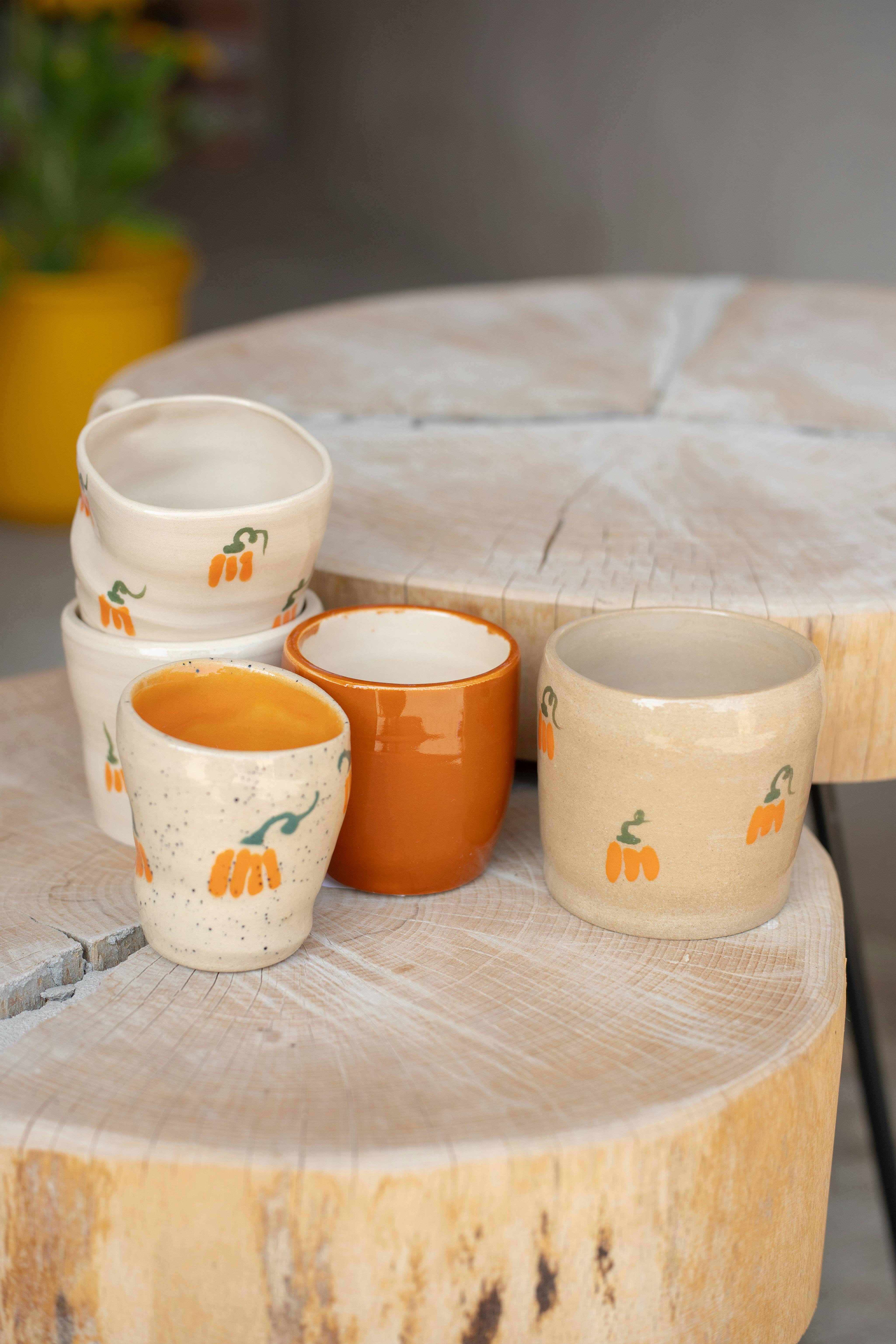 Beautifully handcrafted ceramic mugs with pumpkin designs on a rustic wooden table.
