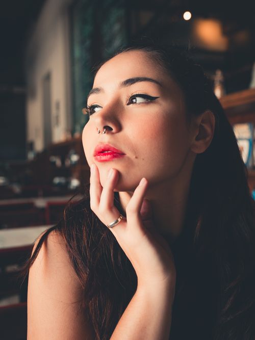 Free Stylish portrait of a woman with red lips, nose piercing, and contemplative expression indoors. Stock Photo