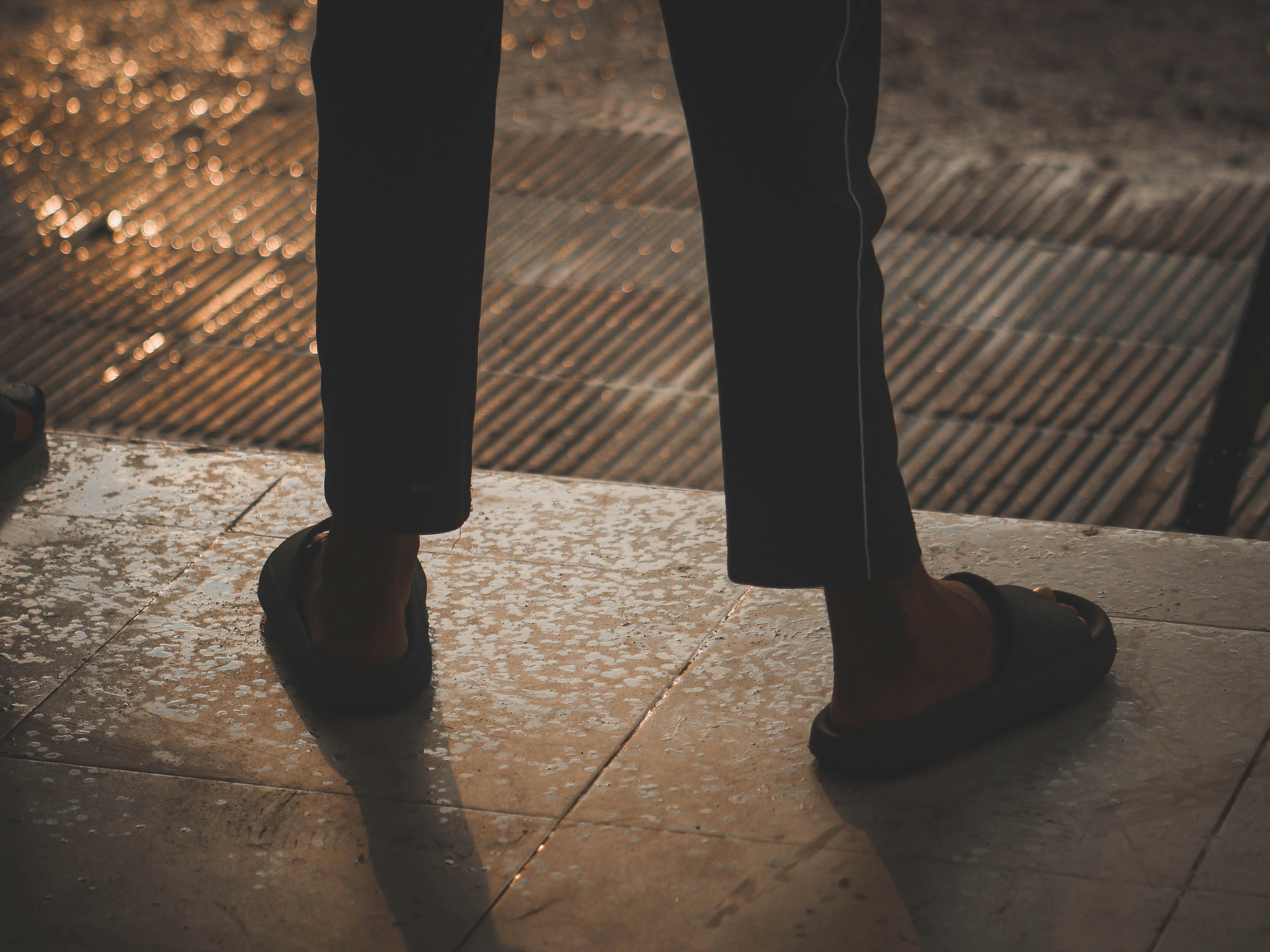 免費 孟加拉國朗布爾，在雨水浸透的人行道上，一個人穿著涼鞋的腳的輪廓。 圖庫相片