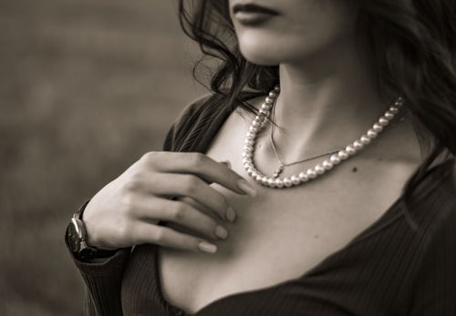 Free Close-up of an elegant woman wearing pearl jewelry in a sepia-toned photo. Stock Photo