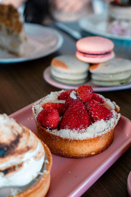 Free Tantalizing dessert setup featuring a strawberry tart and colorful macarons for a delightful treat. Stock Photo