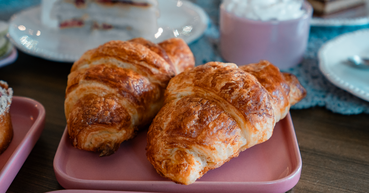 Deliciosos croissants recém-assados servidos em pratos rosas, perfeitos para um ambiente aconchegante de café da manhã.