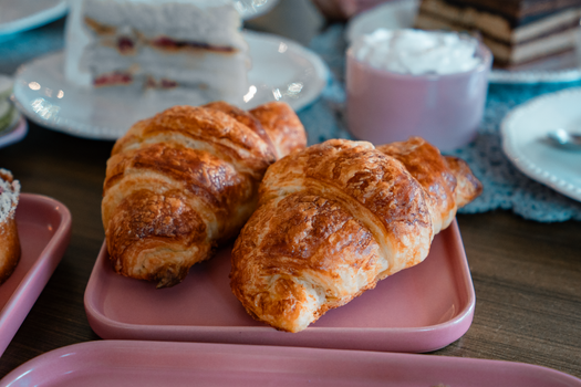Delicious freshly baked croissants served on pink plates, perfect for a cozy breakfast setting.
