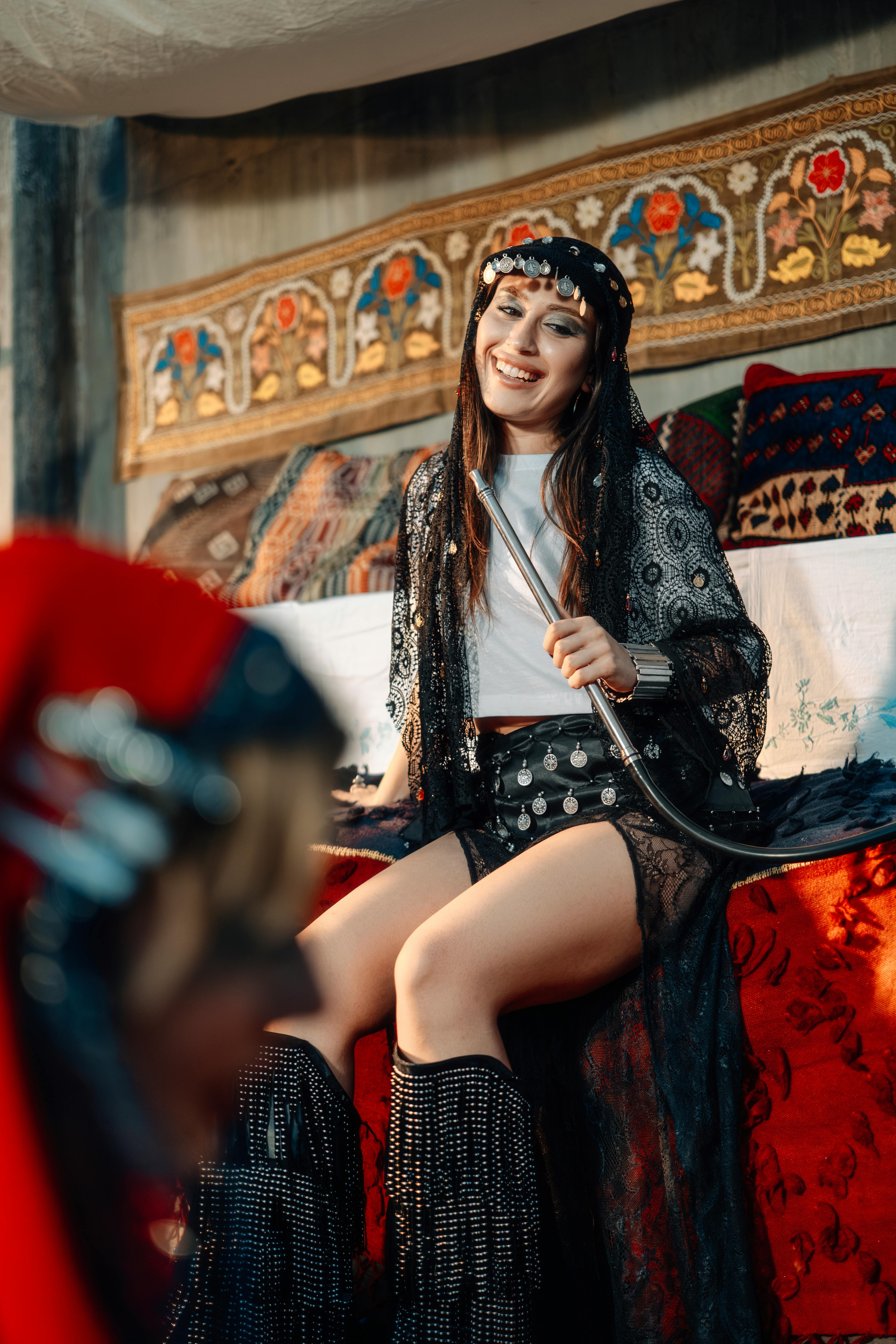 快乐的女人穿着波西米亚风格的服装，坐在装饰有室内的沙发上