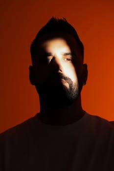 Artistic studio portrait of a bearded man in dramatic lighting with bold colors.
