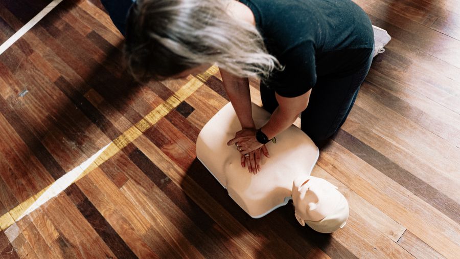 First aid delegate practising CPR technique on a training mannequin during a First Aid at Work course