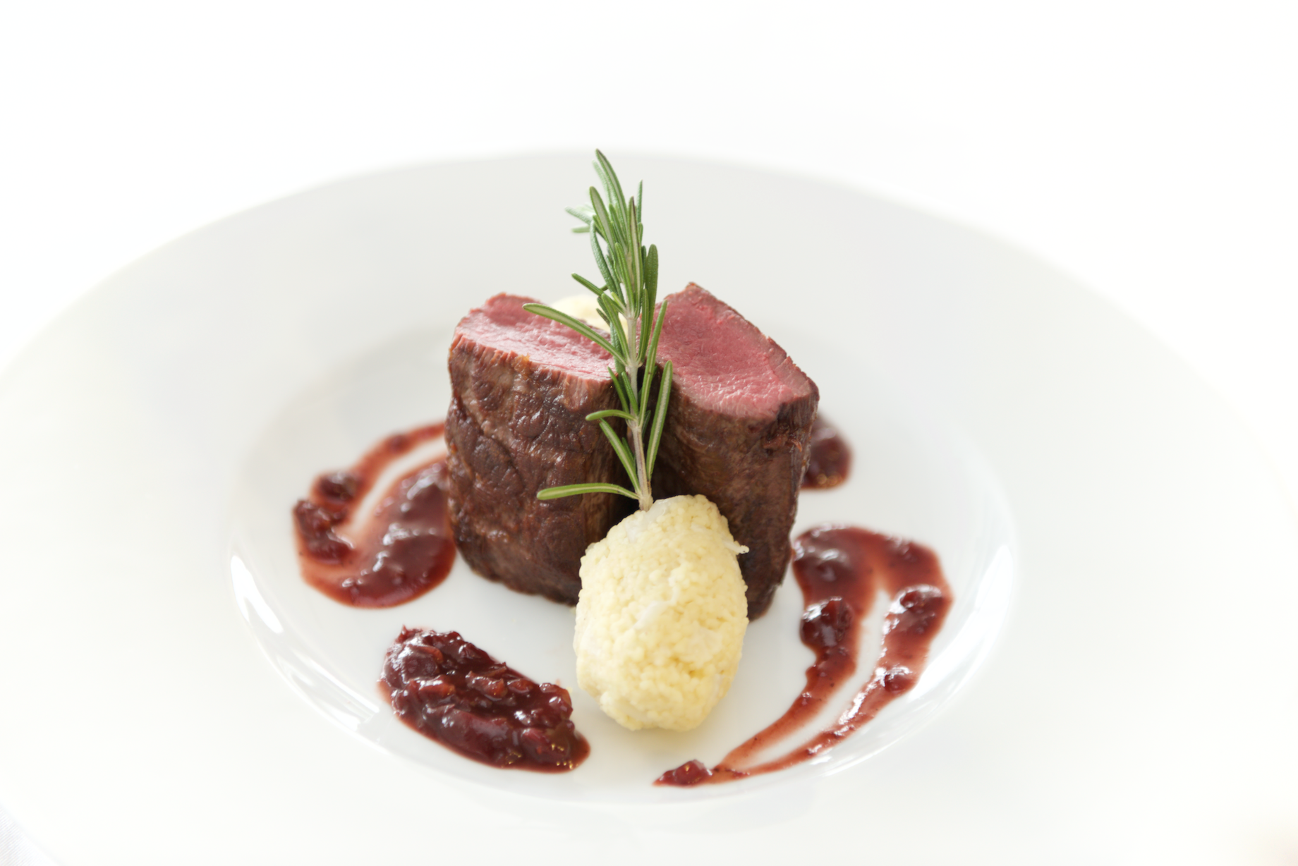 Filet mignon on a wooden cutting board with herbs and grill