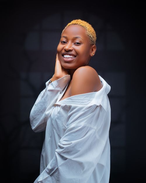 Free A confident woman with short hair smiles brightly in a dark studio setting. Stock Photo