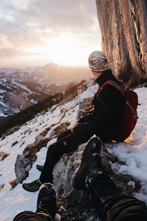 Selective Focus Photography of Man Sitting Snow-capped Mountain