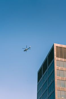 Helicopter flying over downtown Grand Rapids against a clear blue sky, capturing urban architecture.